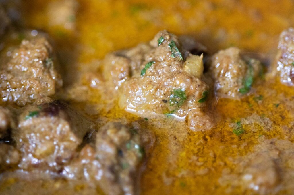 Gros plan d'un curry de bœuf riche avec des herbes et des épices, mettant en valeur sa texture et ses couleurs.