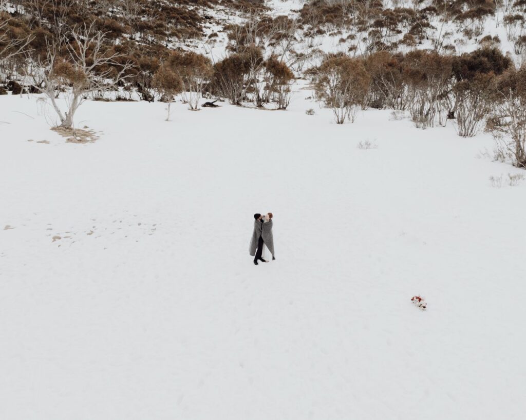 Un couple romantique s'embrassant dans un paysage enneigé, symbolisant l'amour et l'intimité.