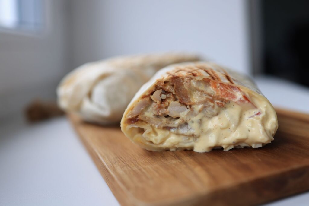 Wrap au poulet savoureux rempli de sauce crémeuse sur une planche à découper en bois.