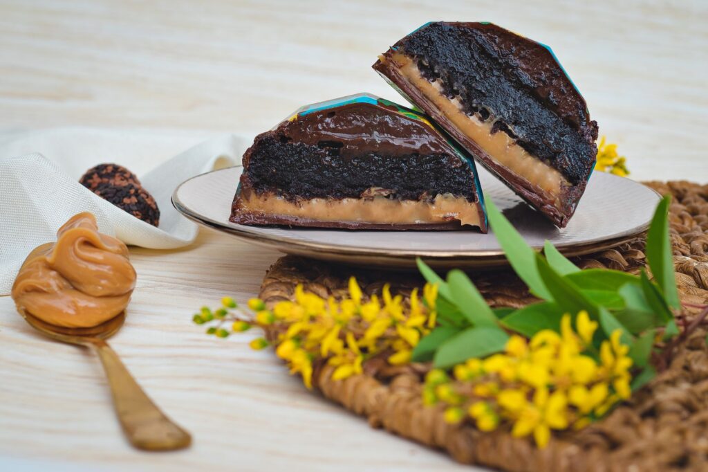 Un délicieux gâteau au chocolat avec une garniture au caramel, servi avec une crème de cacahuète et des fleurs jaunes.