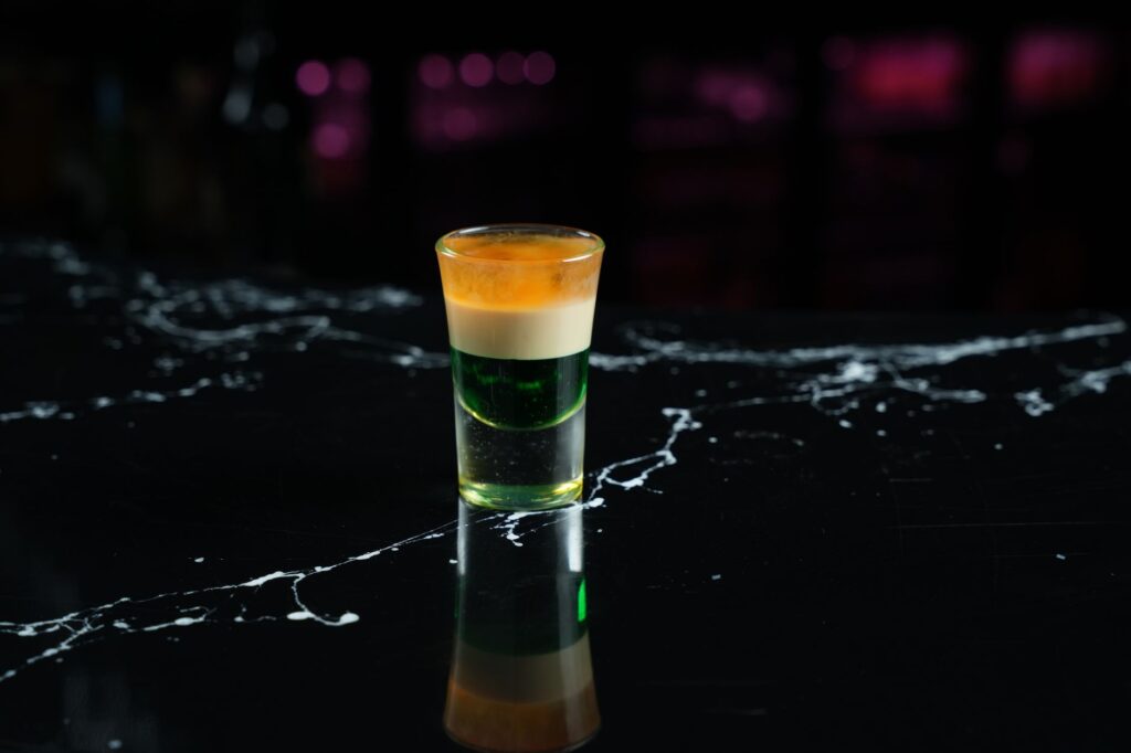 Gros plan d'un cocktail en couches vibrant sur une surface de bar en marbre noir élégant.