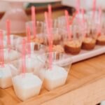Assortiment de mini desserts dans des gobelets transparents avec des cuillères roses, parfait pour les événements de restauration.