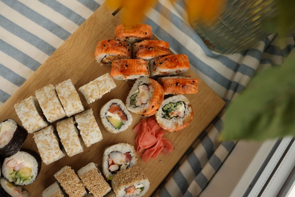 Vue de dessus de divers rouleaux de sushi avec du gingembre sur une planche en bois.