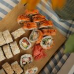 Vue de dessus de divers rouleaux de sushi avec du gingembre sur une planche en bois.