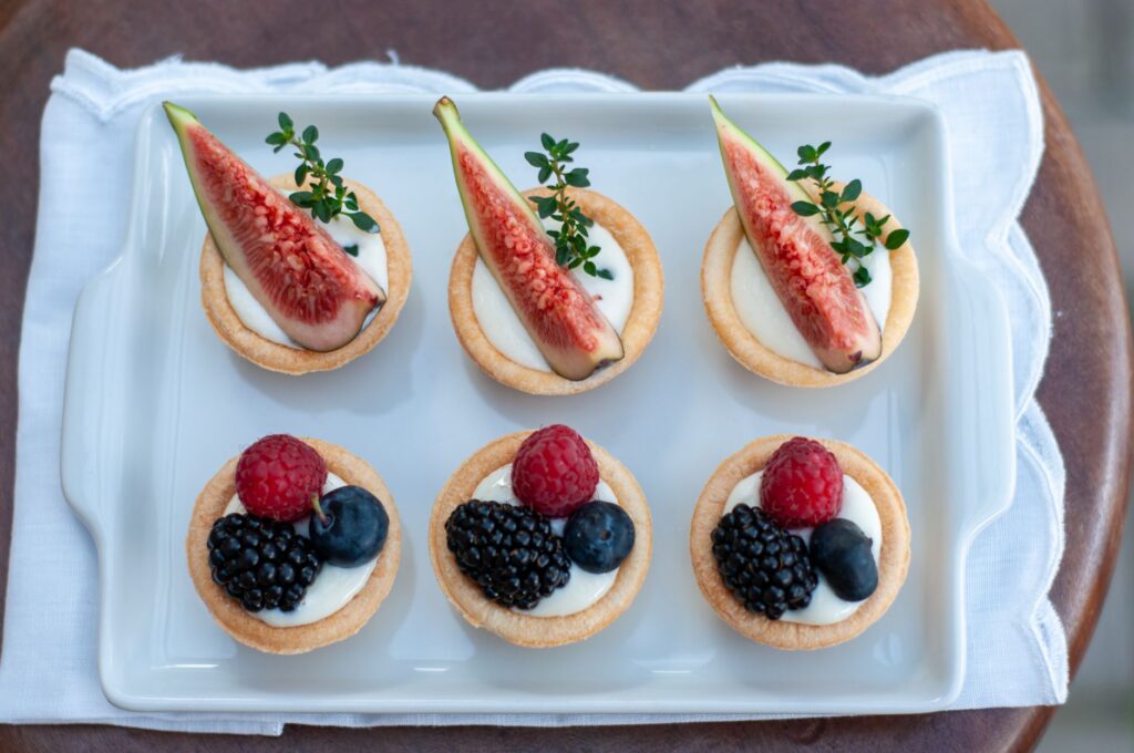 Une plaque de six délicieuses tartes aux fruits garnies de figues fraîches, de framboises, de myrtilles et de mûres.