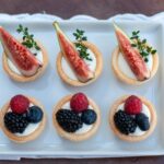 Une plaque de six délicieuses tartes aux fruits garnies de figues fraîches, de framboises, de myrtilles et de mûres.