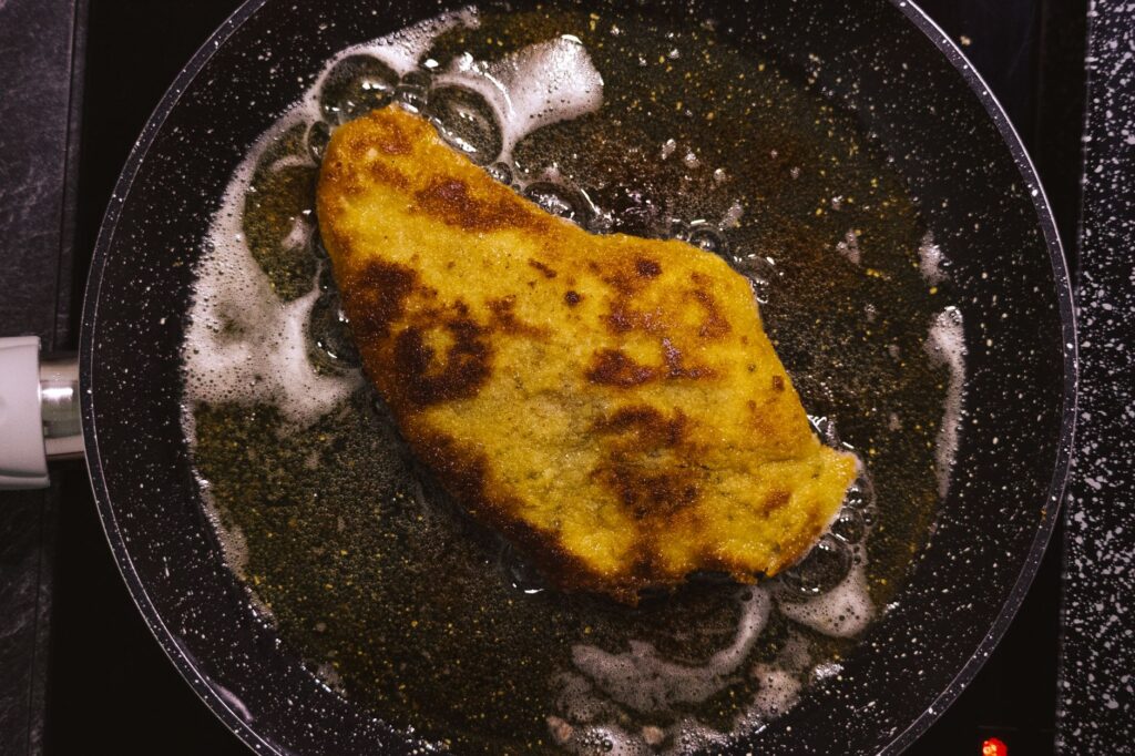 Un schnitzel doré en train de frémir dans une poêle, capturant l'essence de la cuisine réconfortante faite maison.