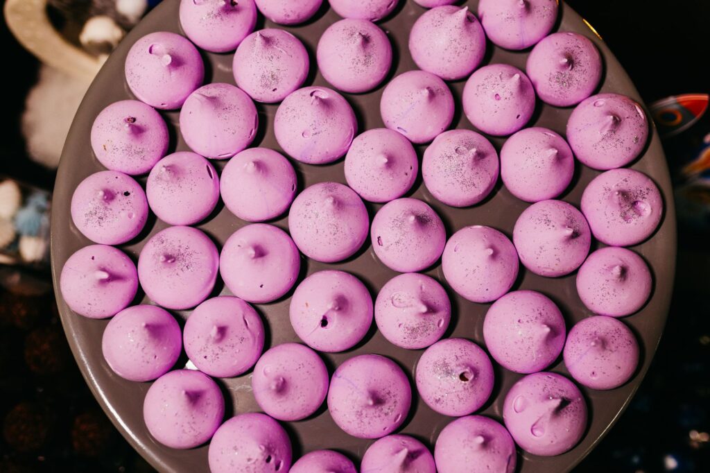 Un plateau rempli de biscuits meringues roses, parfait pour une douce indulgence et la photographie de desserts.