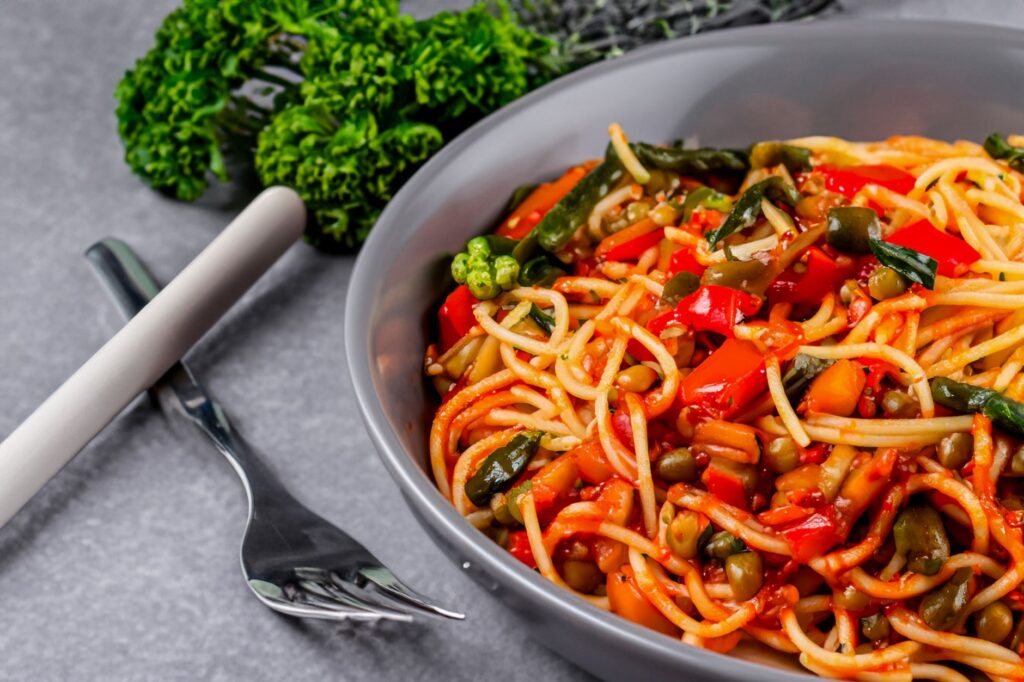 Gros plan sur des pâtes aux légumes savoureuses avec des poivrons et des légumes verts dans un bol. Parfait pour des repas sains ou la photographie culinaire.