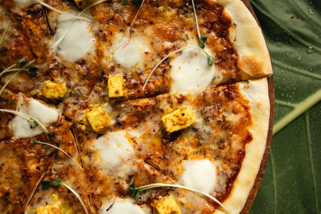 Gros plan d'une pizza paneer alléchante avec des micro-pousses fraîches sur un fond de feuilles.