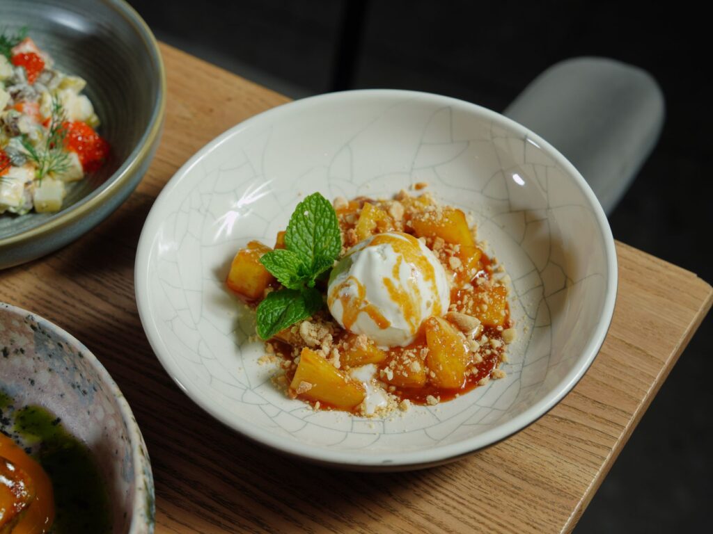 Un dessert somptueux avec de la glace au caramel et des fruits garnis de menthe.