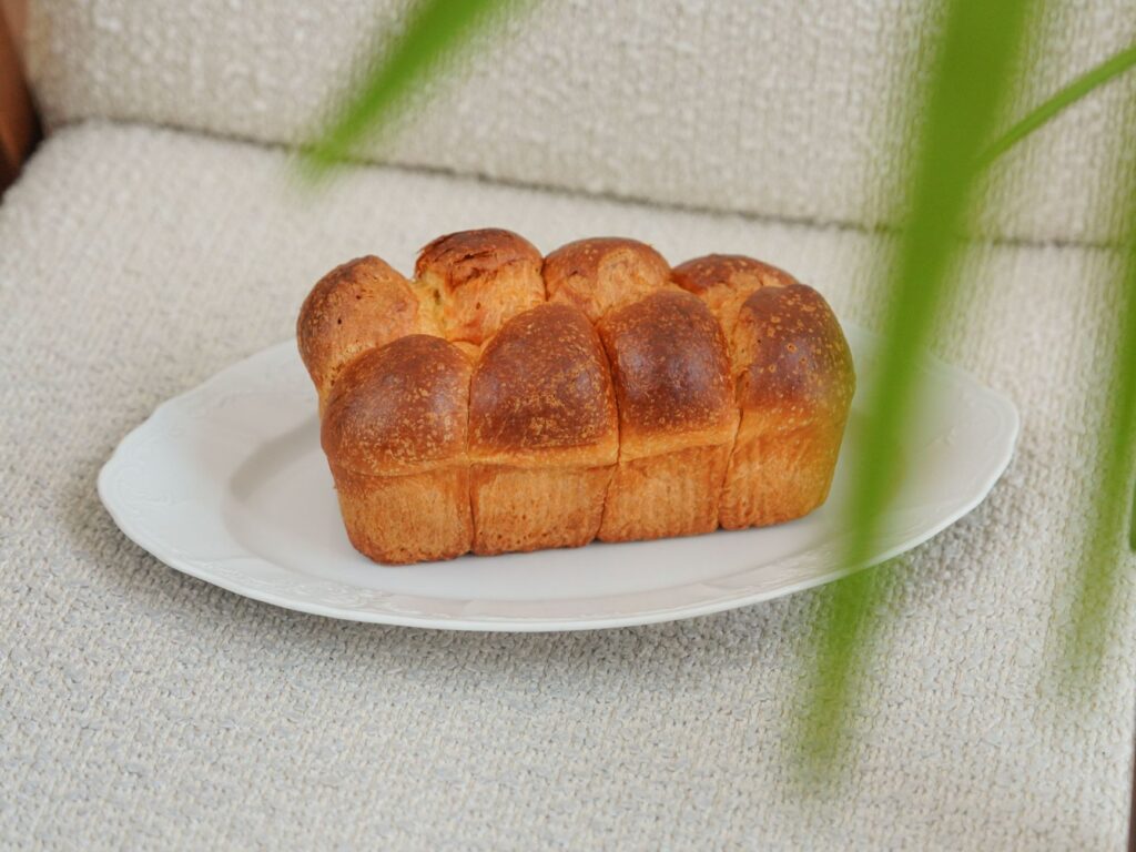 Pain doré sur une assiette blanche avec un arrière-plan chaleureux, idéal pour la photographie culinaire.