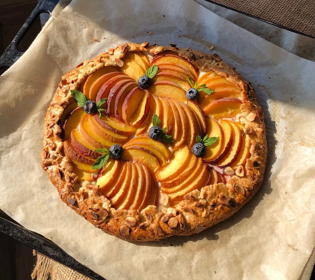 Tarte aux pêches fraîchement cuite garnie de myrtilles, parfaite pour un dessert d'été.