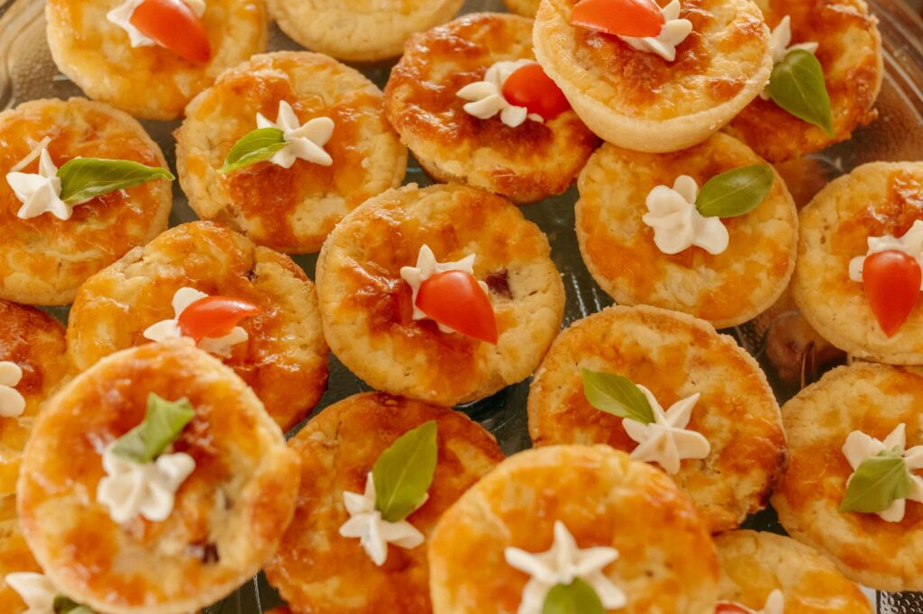 Un assortiment délicieux de mini quiches surmontées d'herbes fraîches et de garnitures au fromage.