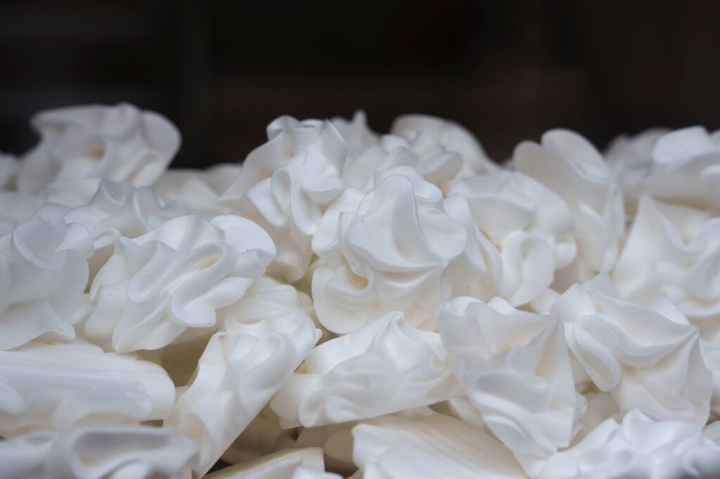 Une image en gros plan détaillée mettant en avant une pile de meringues blanches, soulignant la texture et la douceur.
