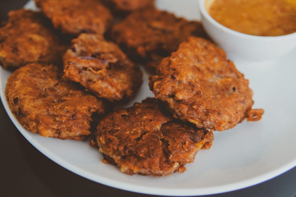 Délicieux beignets frits servis avec une sauce acidulée dans une assiette.