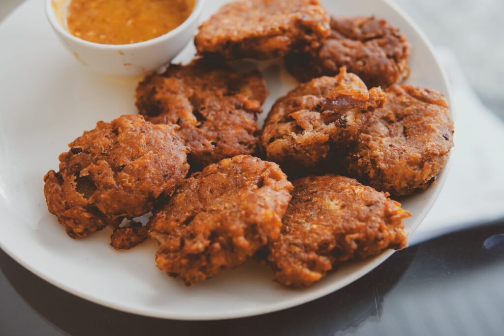 Délicieuses boulettes de viande croustillantes servies sur une assiette blanche avec une sauce piquante.