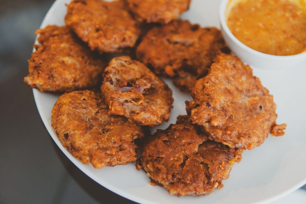 Gros plan sur des beignets croustillants accompagnés d'une sauce acidulée sur une assiette.