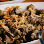 Gros plan sur un sauté de boeuf savoureux avec des légumes mélangés dans un plat de service blanc, parfait pour le dîner.