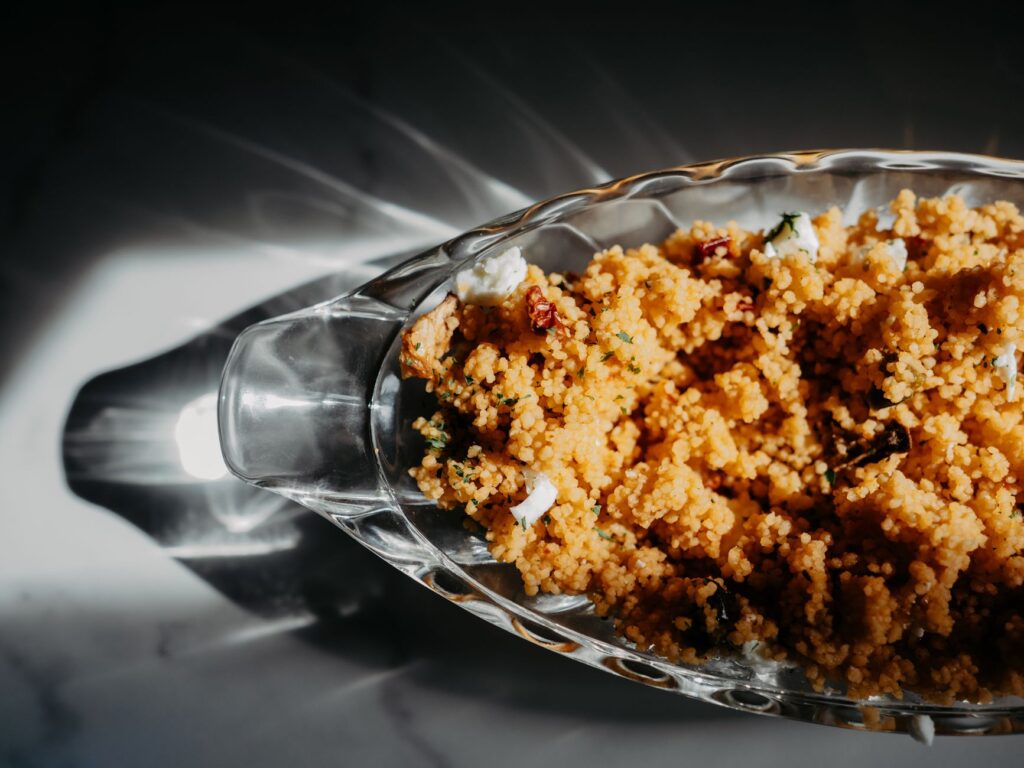 Délicieux couscous maison dans un bol en verre, avec un mélange d'épices et d'herbes. Parfait pour un repas copieux.