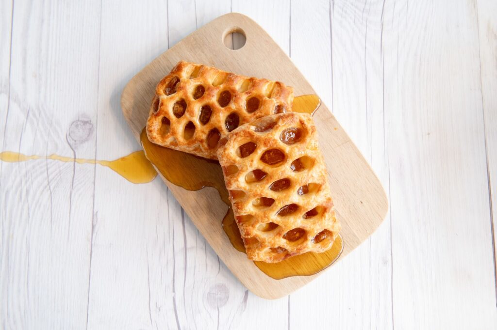Une vue de dessus de délicieuses pâtisseries en treillis avec une garniture sucrée sur une planche à découper en bois.
