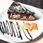 Savourez un gros plan d'une tranche de gâteau au biscuit au chocolat avec une garniture élégante sur une assiette.