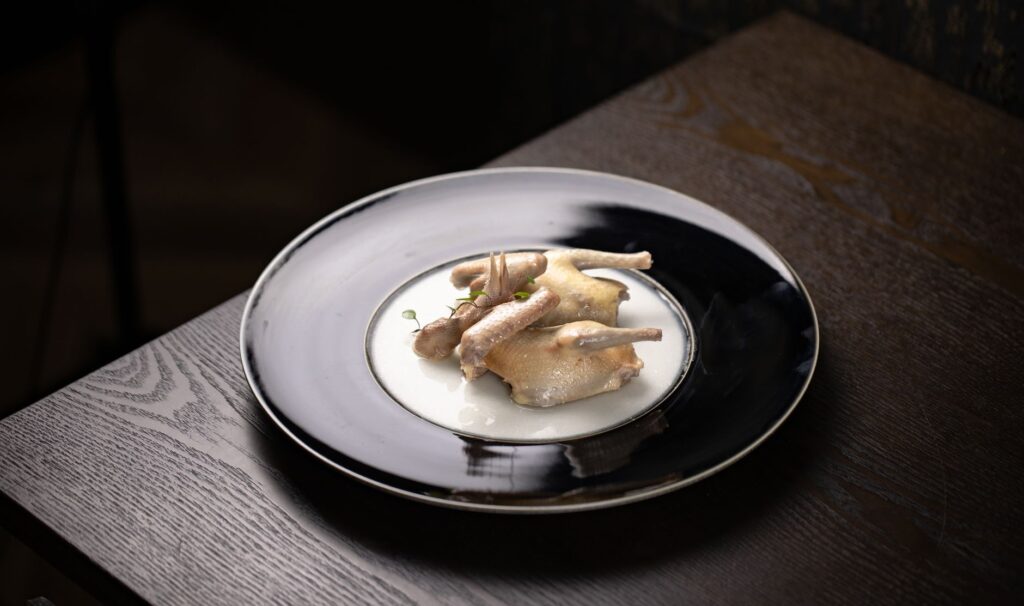 Un plat de pigeons bouillis joliment présenté sur une table en bois, mettant en valeur la photographie culinaire haut de gamme.