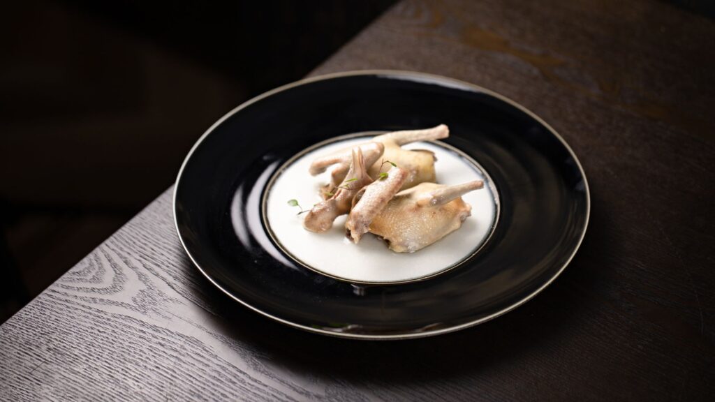 Caille artistiquement présentée sur une élégante assiette noire, parfaite pour des concepts de gastronomie.