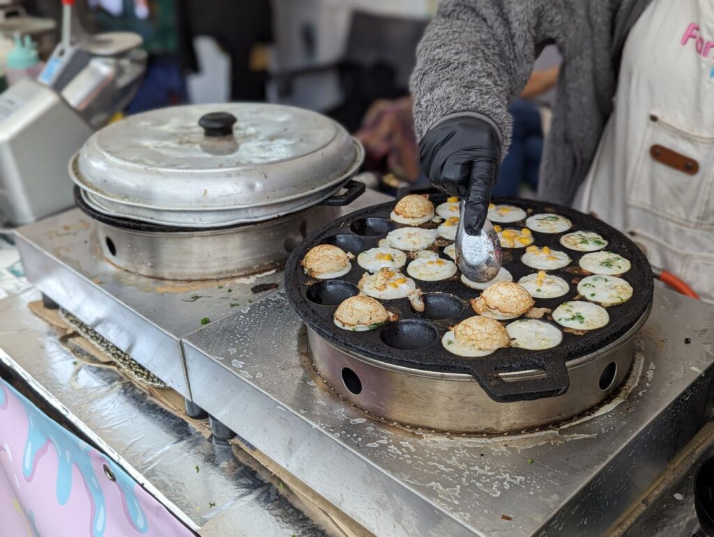 Gros plan sur un vendeur préparant des pancakes thaïlandais Khanom Krok dans un marché en plein air à Leipzig.