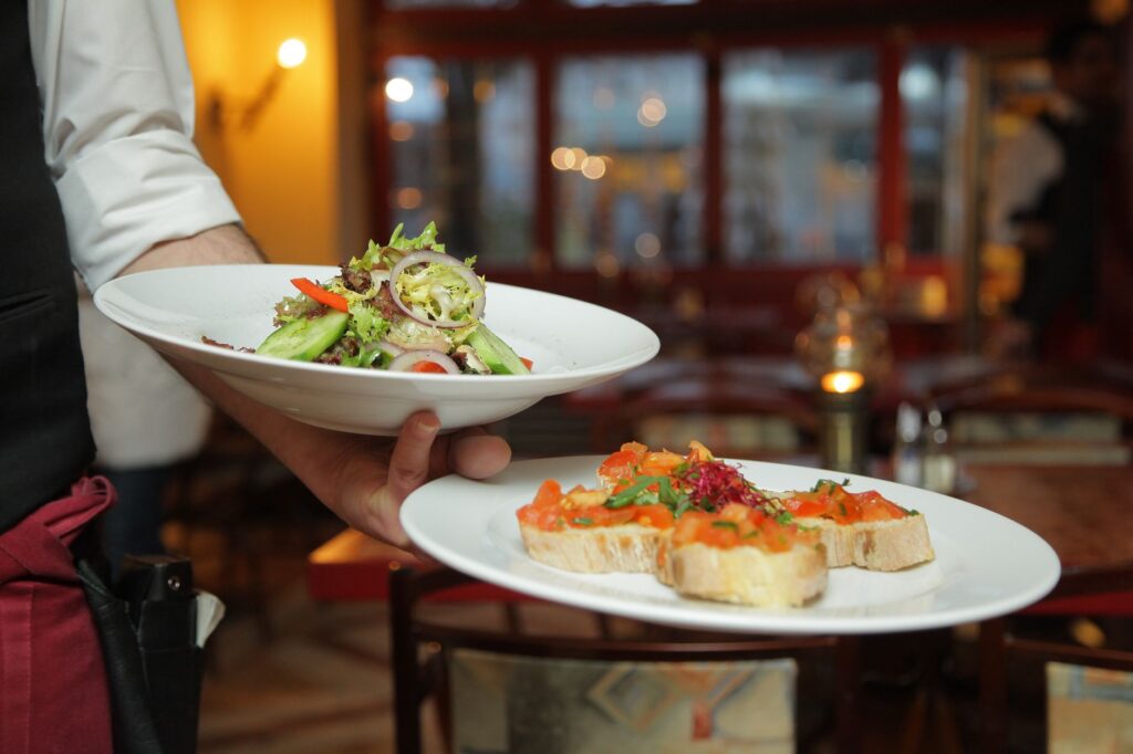 Un serveur apporte une salade fraîche et des hors-d'œuvre dans un cadre de restaurant confortable.