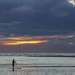 Silhouette d'un paddle boarder pendant le lever du soleil à St. Simons Island, Georgia.