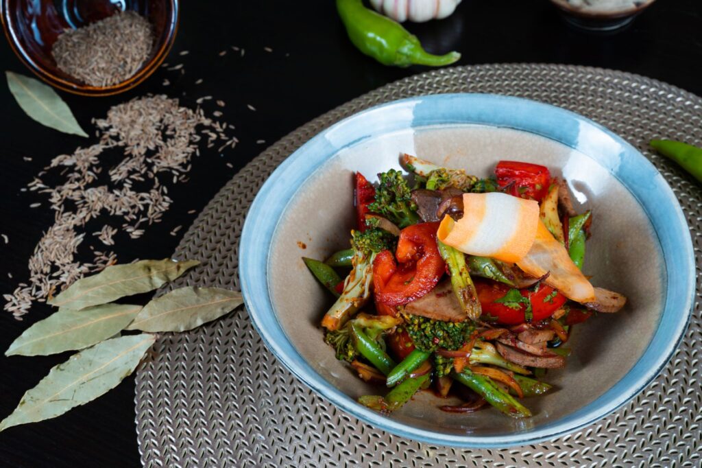 Un sauté de légumes vibrant dans un bol, entouré d'épices et d'herbes, prêt pour un repas sain.