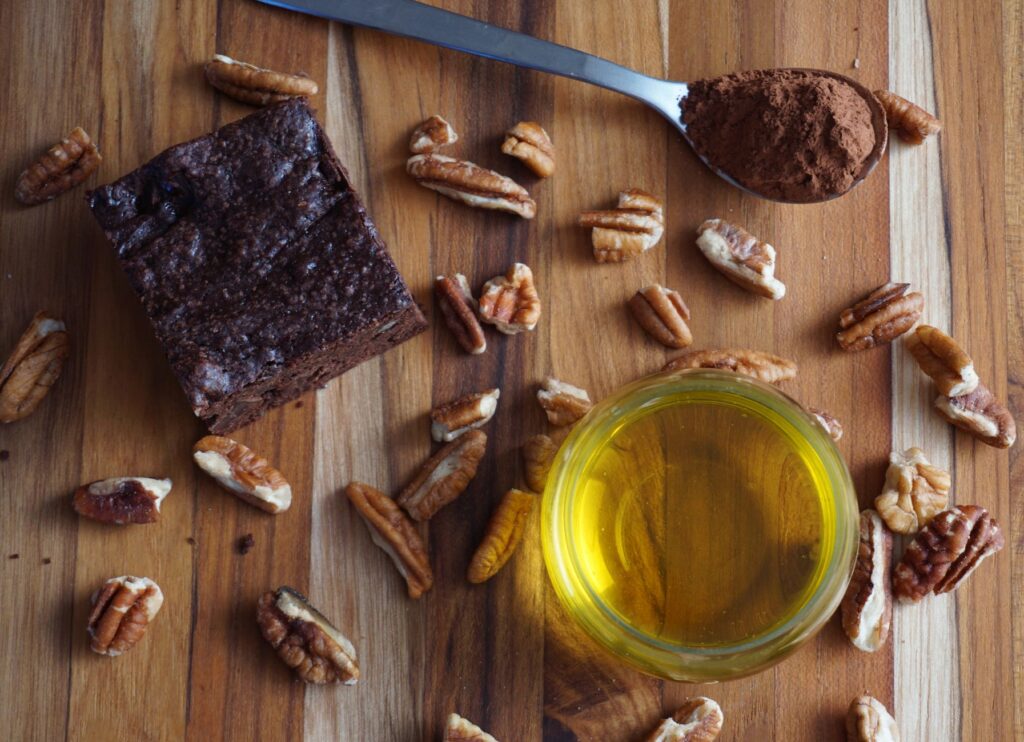 Vue à plat d'un brownie au chocolat fait maison avec des pacanes, du cacao et de l'huile. Parfait pour des visuels de pâtisserie.