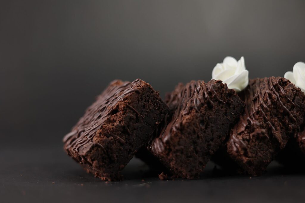 Gros plan sur de riches brownies au chocolat garnis d'une cuillerée de crème fouettée.
