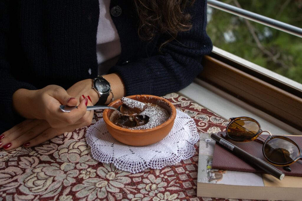 Un moment chaleureux dégustant un dessert au chocolat près d'une fenêtre avec vue, mettant en avant des accessoires stylisés.