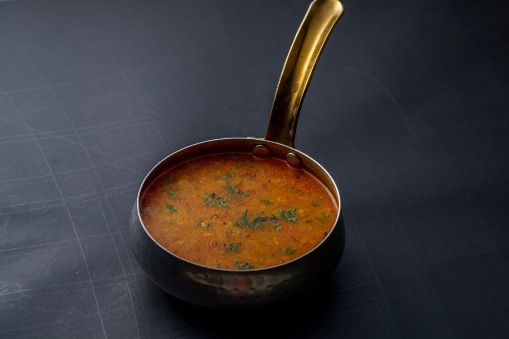 Un gros plan de dal indien garnie d'herbes dans un pot en cuivre, offrant un goût de la cuisine traditionnelle.