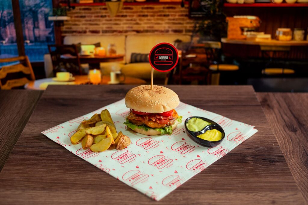 Burger gourmet avec frites et sauce dans un cadre de café élégant, parfait pour les amateurs de bonne cuisine.