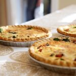 Délicieuses quiches maison sur une nappe à motifs classiques, accueillantes et savoureuses.