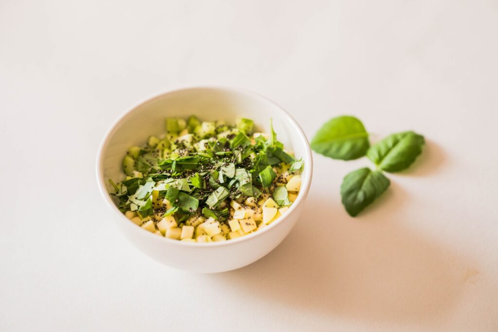 Une salade verte rafraîchissante dans un bol blanc avec des herbes fraîches et des graines, parfaite pour un repas sain.