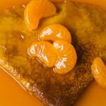 Gros plan d'une délicieuse crêpe garnie de tranches de mandarine juteuses dans un sirop sucré.