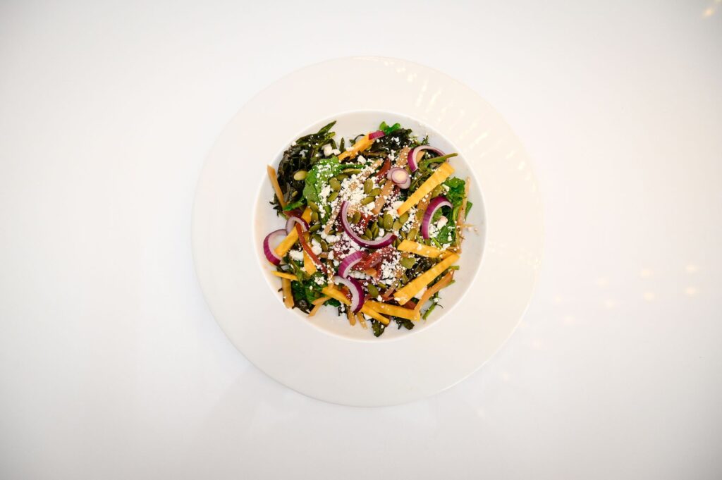 Vue de dessus d'une salade de légumes colorée et nutritive avec diverses garnitures sur une assiette blanche.