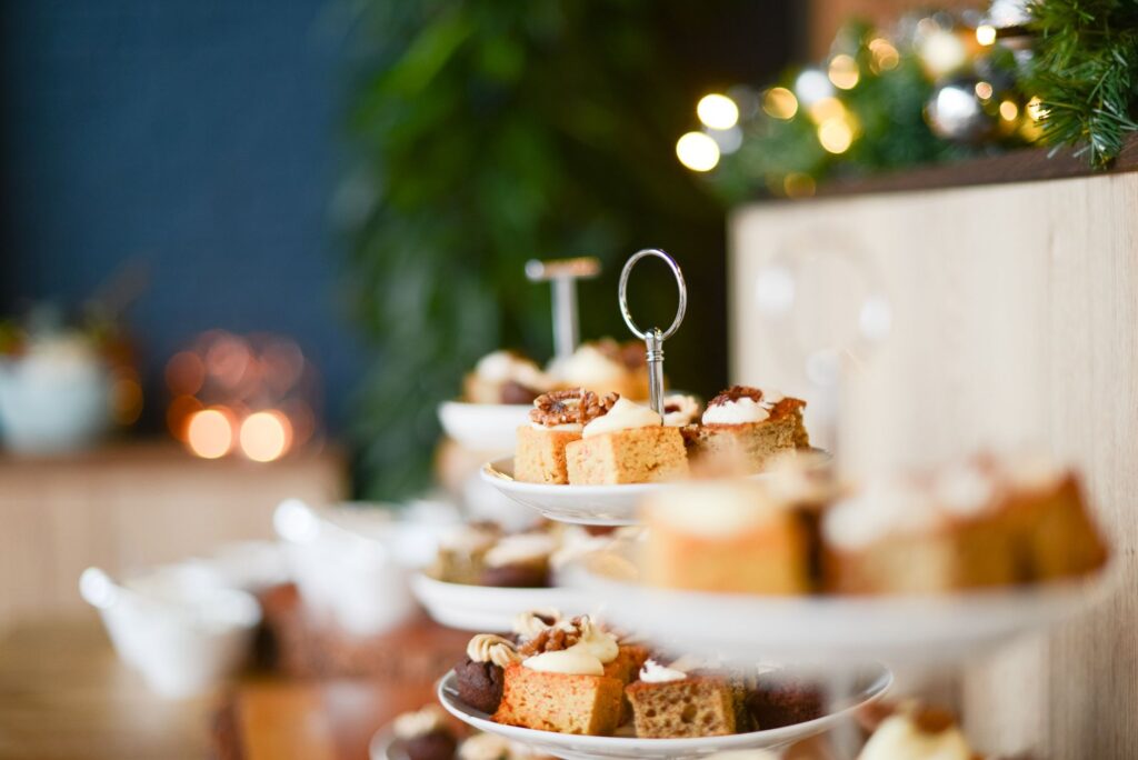 Gros plan d'un assortiment de gâteaux festifs sur un support à étagères avec des lumières bokeh.