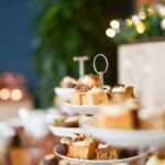 Gros plan d'un assortiment de gâteaux festifs sur un support à étagères avec des lumières bokeh.
