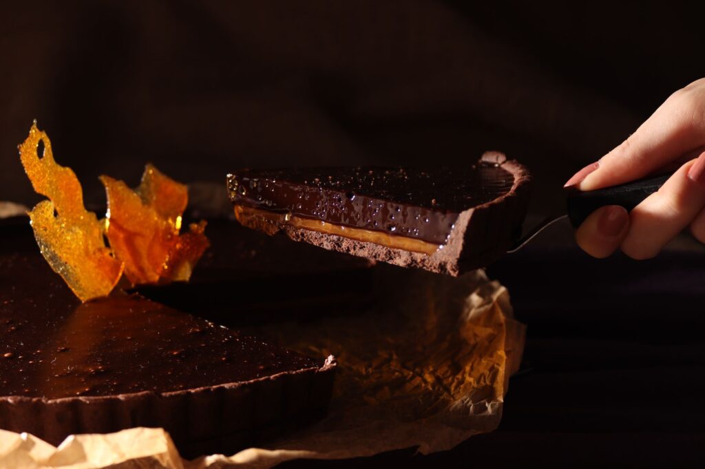 Gros plan sur une tranche de tarte au chocolat riche avec du caramel, parfaite pour les desserts ou les blogs culinaires.