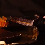 Gros plan sur une tranche de tarte au chocolat riche avec du caramel, parfaite pour les desserts ou les blogs culinaires.