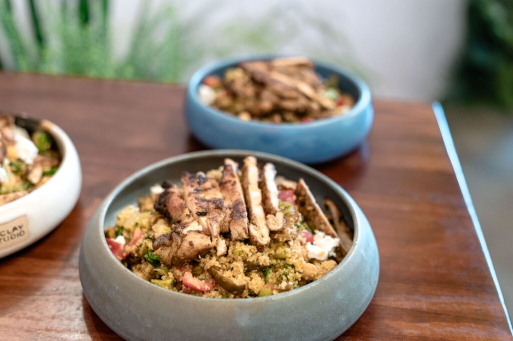 Une délicieuse salade de quinoa avec du poulet grillé succulent servi dans d'élégants bols en céramique sur une table en bois.