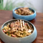 Une délicieuse salade de quinoa avec du poulet grillé succulent servi dans d'élégants bols en céramique sur une table en bois.