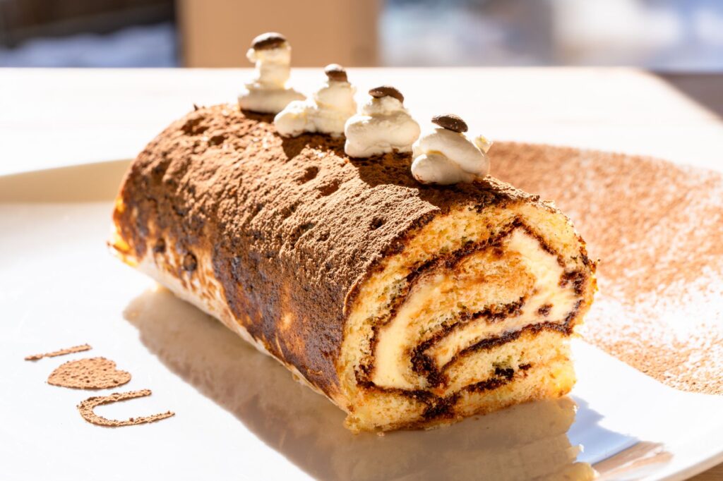 Gros plan d'un rouleau suisse tiramisu fait maison avec garniture à la crème et au cacao.