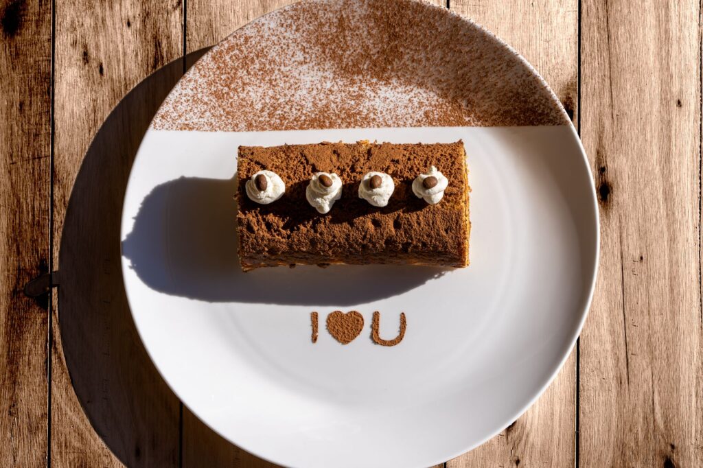 Délicieux tiramisu avec le message « I ❤️ U » sur une assiette ensoleillée, parfait pour la Saint-Valentin.