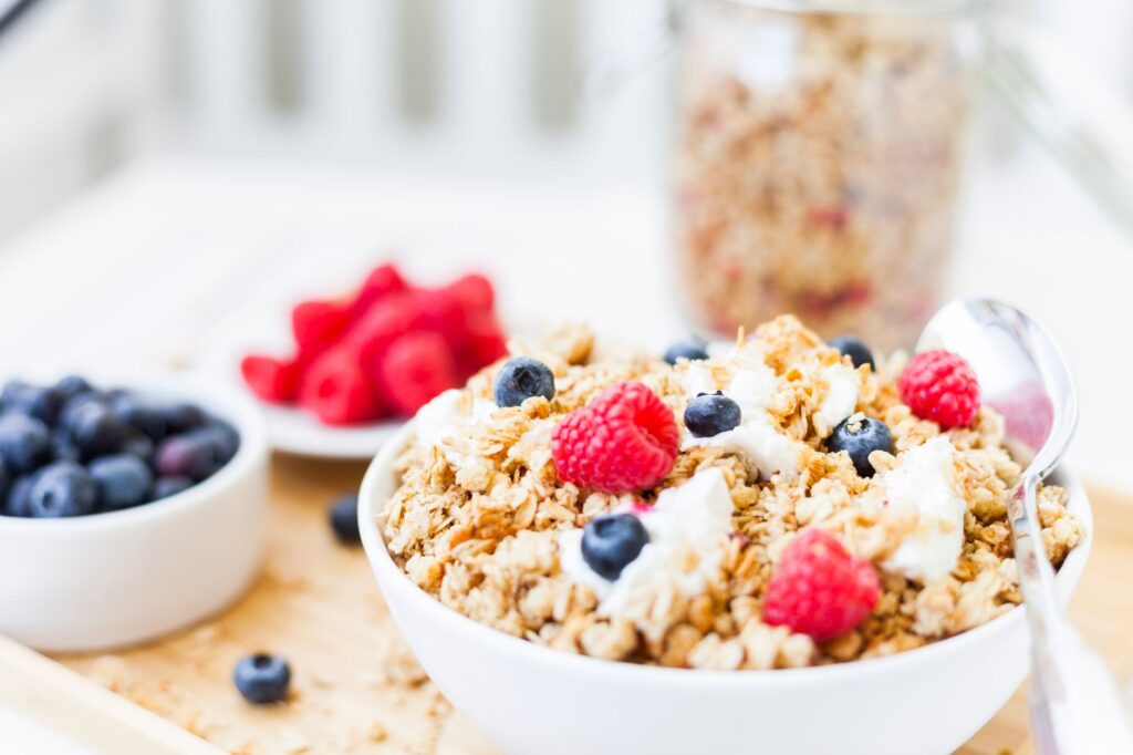 Bol de petit-déjeuner granola sain garni de framboises et de myrtilles fraîches.